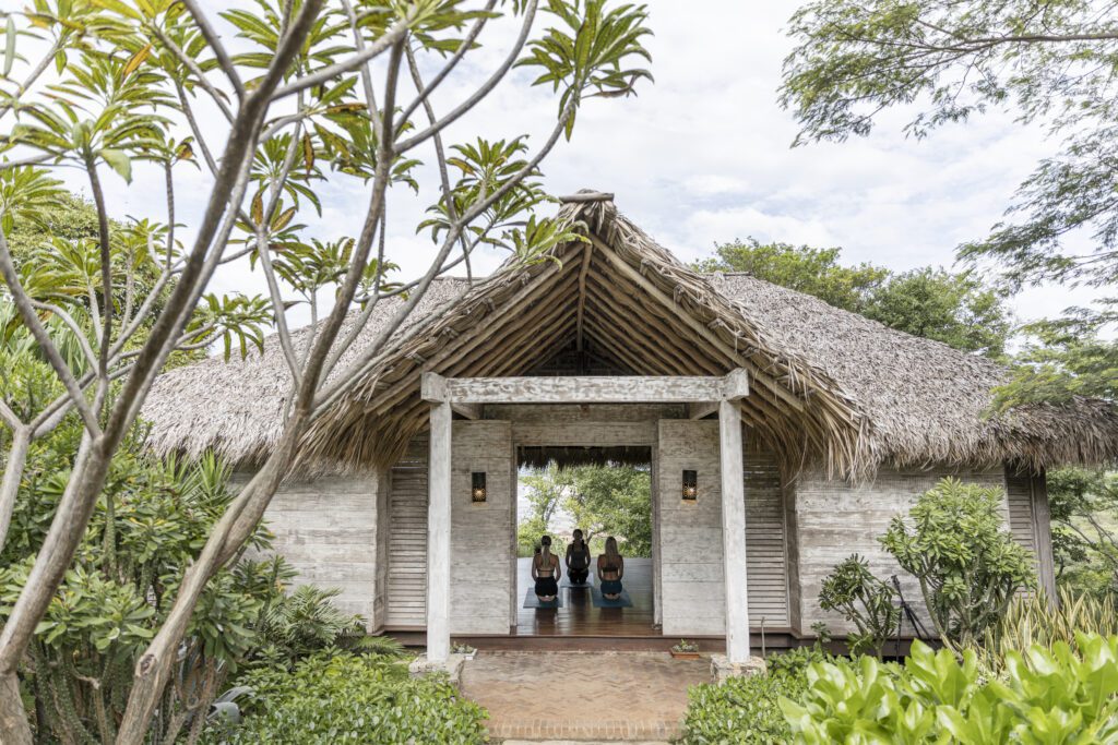 three women holding a yoga pose at Rancho santana wellness resort.